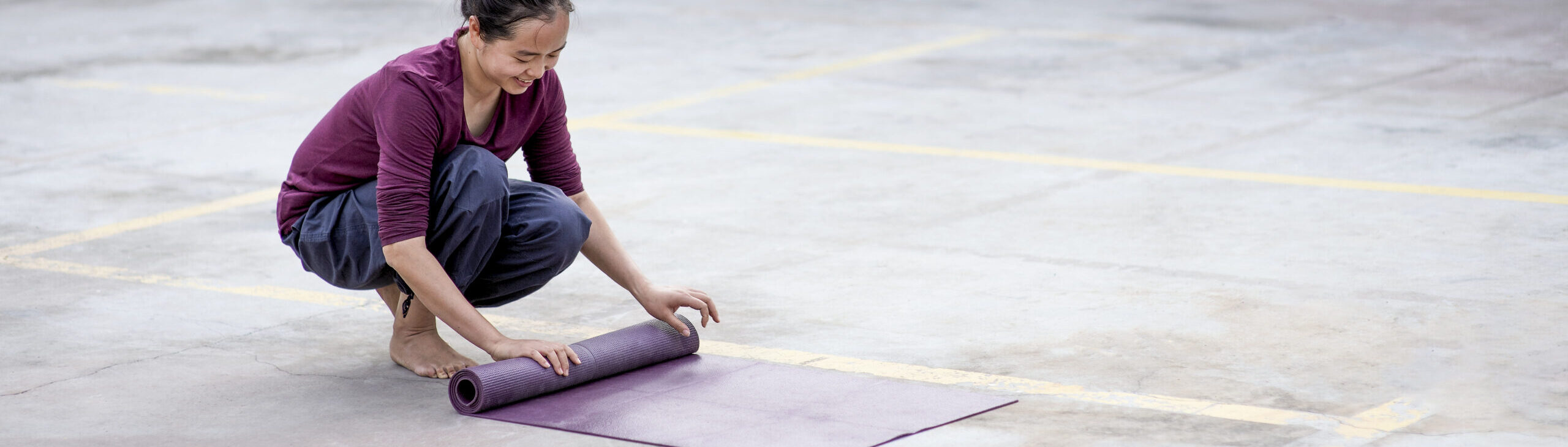 A student rolling out a yoga mat before practice